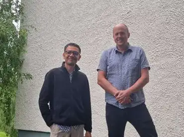 Julius Dimabayao with Scientist-in-charge Dr. Anders Romundset posing in the foreground for a photo in NGU. Behind them is the building for NGU.